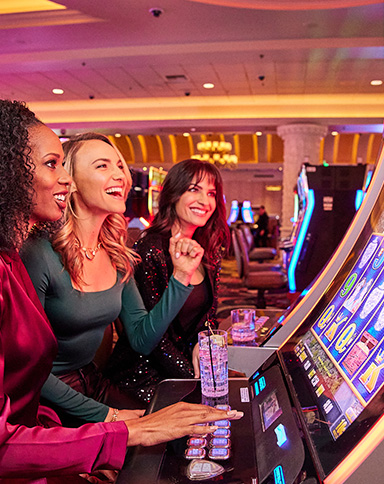 three women smiling in the casino playing slots
